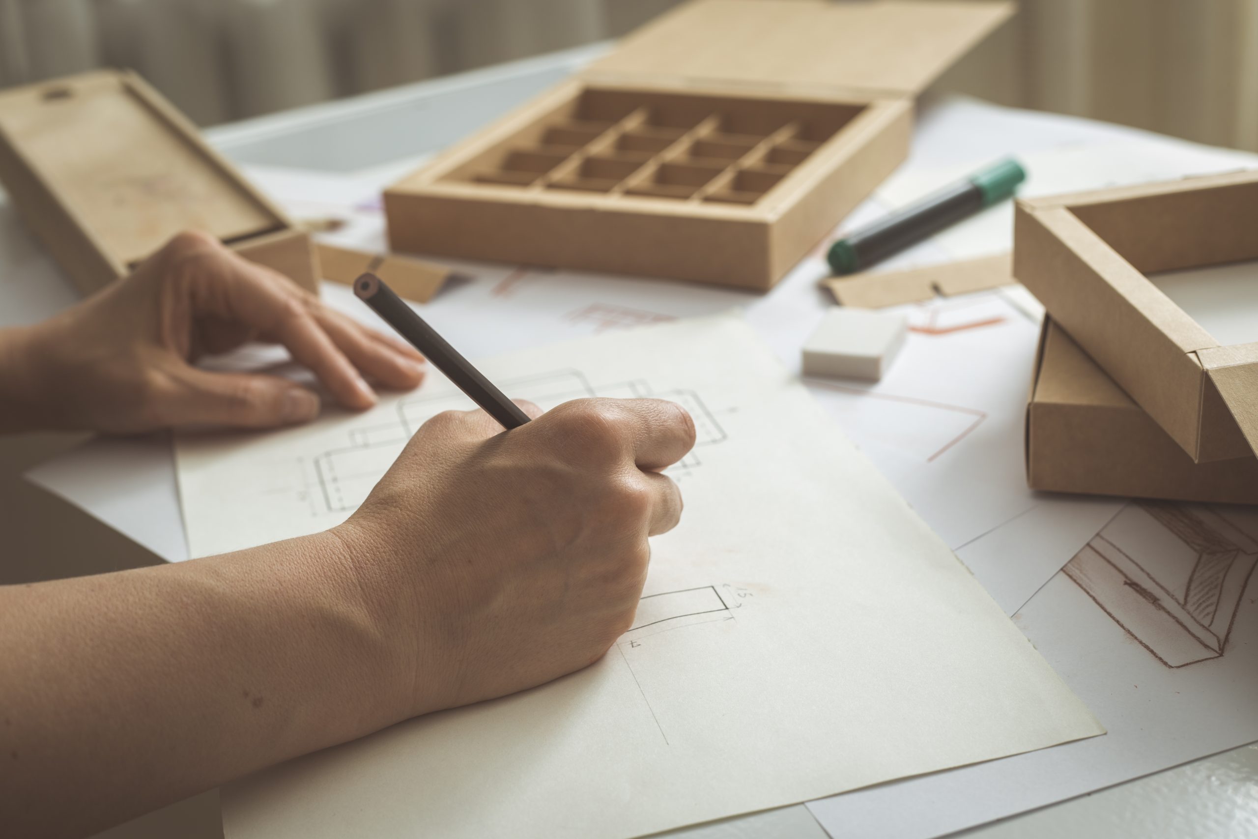 designer-draws-sketches-cardboard-packaging
