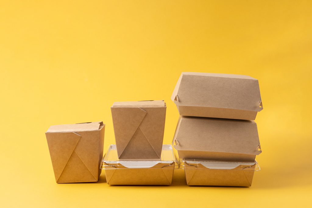 Disposable food delivery boxes on yellow background Disposable food delivery boxes on yellow background